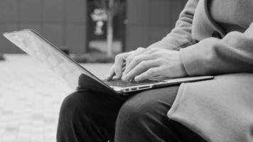 Business person types on a laptop keyboard. Type background. Modern office worker using a laptop, typing a text black and white footage video