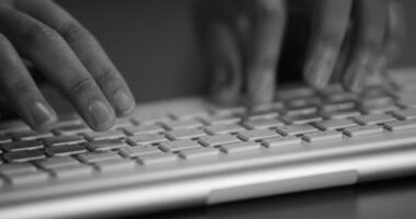 Business person types on a laptop keyboard. Type background. Modern office worker using a laptop, typing a text black and white footage video