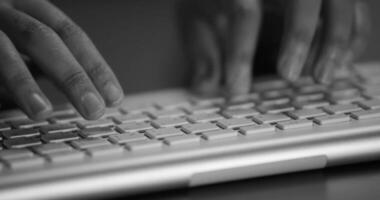 Business person types on a laptop keyboard. Type background. Modern office worker using a laptop, typing a text black and white footage video