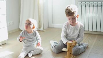 pré escola Garoto e menina jogando em chão com de madeira brinquedos. crianças crianças às casa ou creche video