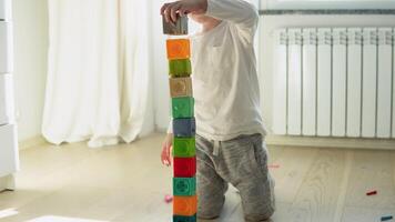 wenig Junge Gebäude Turm von Block Spielzeuge Sitzung auf Fußboden im sonnig Schlafzimmer video