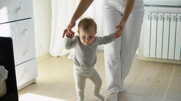 Baby taking first steps with mother's help at home video