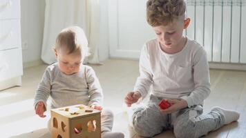 Two kids boy and girl playing with wooden shape sorter video