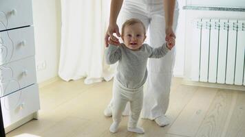 Baby taking first steps with mother's help at home video