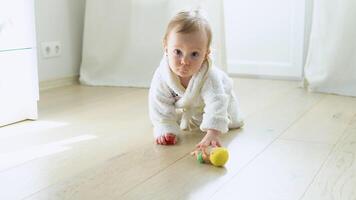 Kid girl playing with a doll at home or kindergarten. Cute child in bathrobe playing on the floor in nursery video