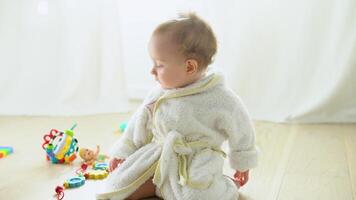 Cute child in bathrobe playing on the floor in nursery video