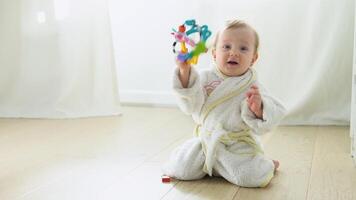 Kid girl playing toys at home or kindergarten. Cute child in bathrobe playing on the floor in nursery video