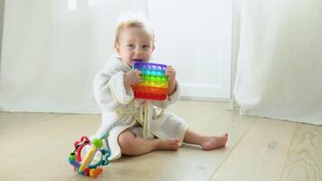 Little girl in bathrobe playing with educational toy. Cute girl playing intellectual toys video