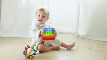 Little girl playing with educational toy. Cute girl in bathrobe playing intellectual toys video