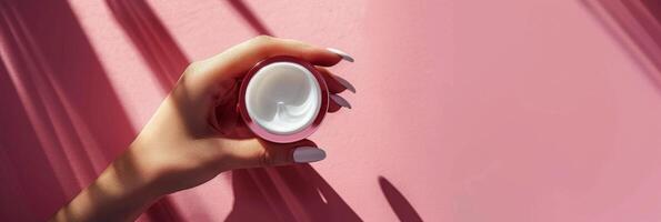 Womans Hands Holding Jar of Cream by Pink Flowers photo