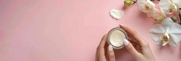 Hand Holding Jar of Cream Next to Flowers photo