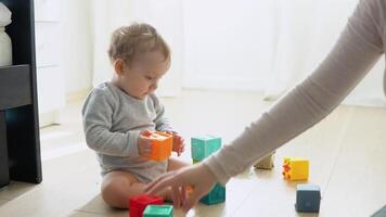 niño jugando con vistoso juguete bloques con madre. niños jugar. educativo juego para bebé y niñito video