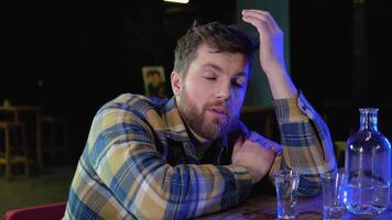 A man sitting at a bar drinking shots or vodka. Drinking, going out, inclusivity and alcohol concept video