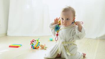 linda niño en bata de baño jugando en el piso en guardería video