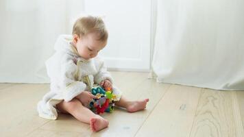 Kid girl in bathrobe playing toys at home or kindergarten. Cute child playing on the floor in nursery video