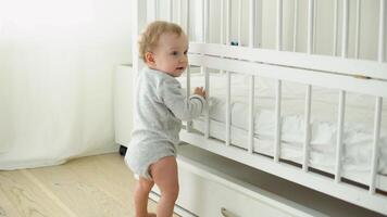 Baby taking first steps near the bed. Little girl learning to walk video