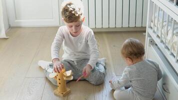 pré escola Garoto e menina jogando em chão com de madeira brinquedos. crianças crianças às casa ou creche video