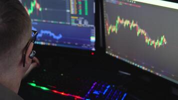 Happy stock broker sitting near monitor with cryptocurrency information data on finance market graph. Trader celebrating a successful trade video