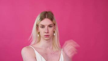 Portrait close up of young transgender man in a dress on a pink background video