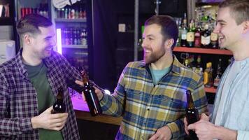 groupe de content Jeune Hommes en buvant du froid Brouillon bière, bavardage et ayant bien temps à pub. souriant insouciant copains profiter en buvant ensemble dans bar video