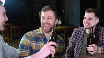 Group of happy young men drinking cold draft beer, chatting and having good time at pub. Smiling carefree friends enjoying drinking together in bar video