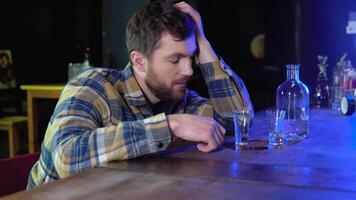 A very drunk man sits in a bar with a glass of vodka or shots video