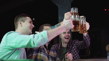 Group of happy young men drinking cold draft beer, chatting and having good time at pub. Smiling carefree friends enjoying drinking together in bar video