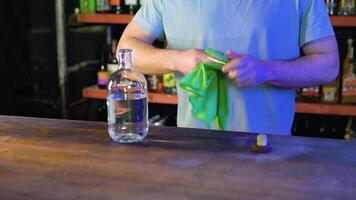 Service at pub. Attractive barman wipes empty glass, standing at bar in interior video
