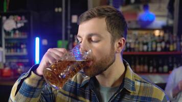 retrato do uma bonito caucasiano jovem homem bebendo saboroso dourado refrescante Cerveja bebida dentro uma bar video