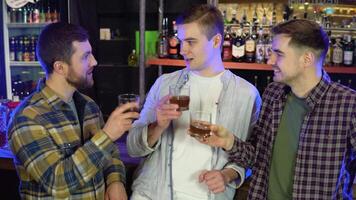 tre vänner i en bar chattar och häller whisky från glasögon video