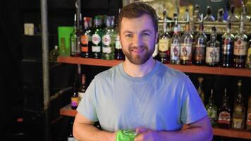 Service at pub. Attractive barman wipes empty glass, standing at bar in interior video