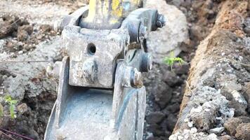 Excavator digs a trench to lay pipes. Close up of an excavator digging a deep trench. An excavator digs a trench in the countryside to lay a water pipe. Slow motion video