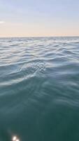 Sea water surface. Low angle view from kayak, camera flies over clear calm sea water. Nobody. Holiday recreation concept. Abstract nautical summer ocean nature. Slow motion. Close up. Vertical video