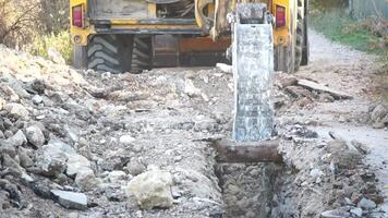 Excavator digs a trench to lay pipes. Close up of an excavator digging a deep trench. An excavator digs a trench in the countryside to lay a water pipe. Slow motion video