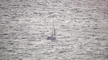 jacht Aan kalmte zonsondergang zee. luxe reis reis. kant visie van wit boot Aan diep blauw water. antenne visie van rijk jacht het zeilen zee. zomer reis Aan luxe schip. langzaam beweging video