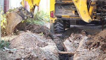 excavador alojamiento un zanja a laico tubería. cerca arriba de un excavador excavación un profundo zanja. un excavador alojamiento un zanja en el campo a laico un agua tubo. video