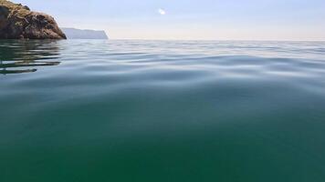 Sea water surface. Low angle view over clear azure sea water. Sun glare. Abstract nautical summer ocean nature. Holiday, vacation and travel concept. Nobody. Slow motion. Weather and climate change video