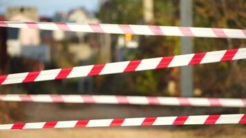 Red and white warning tape swinging in the wind. Protection sign. Don't cross the line. Red White caution tape pole fencing is protects for No entry. Backdrop without people, empty street. video