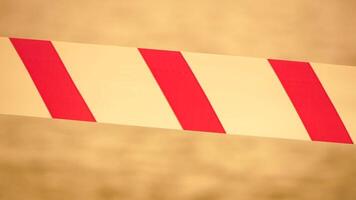 Red white warning tape barrier ribbon swinging in the wind across exotic sea beach background without people. No entry Red White caution tape. No holiday concept, delayed travel, no summer plans video