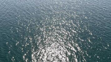 Sea water surface. Aerial view over clear azure sea water. Sun glare. Abstract nautical summer ocean nature. Holiday, vacation and travel concept. Nobody. Slow motion. Weather and climate change video