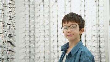 Portrait of a little boy in optics store in new glasses. Ophthalmology concept video