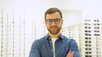 content Jeune Masculin client met Nouveau des lunettes près grille et vitrine avec lunettes. satisfait client video