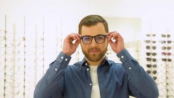 content Jeune Masculin client met Nouveau des lunettes près grille et vitrine avec lunettes. satisfait client video