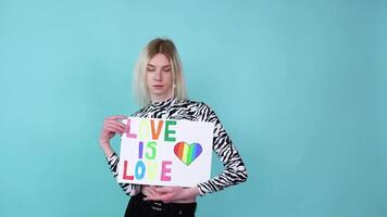 Young transgender man holding paper with love is love message video