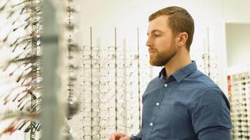 Health care, eyesight and vision concept - a man choosing glasses at optics store video