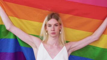 hermoso joven Transgénero hombre levantando arco iris bandera desde su cabeza en el aire video
