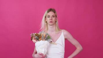 Transgender man with flowers against pink background video