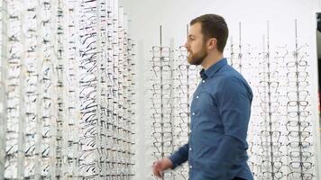 saúde Cuidado, visão e visão conceito - uma homem escolhendo óculos às óptica loja video