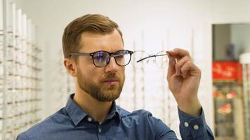 engraçado homem escolhendo óculos às óptica loja. saúde Cuidado, visão e visão conceito video