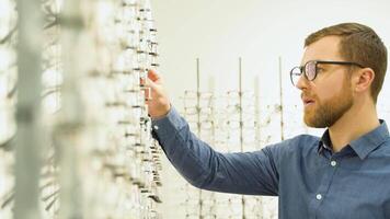 Health care, eyesight and vision concept - a man choosing glasses at optics store video